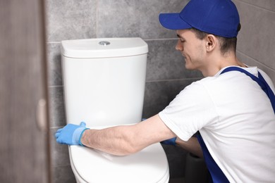 Photo of Plumber wearing protective gloves repairing toilet bowl in water closet