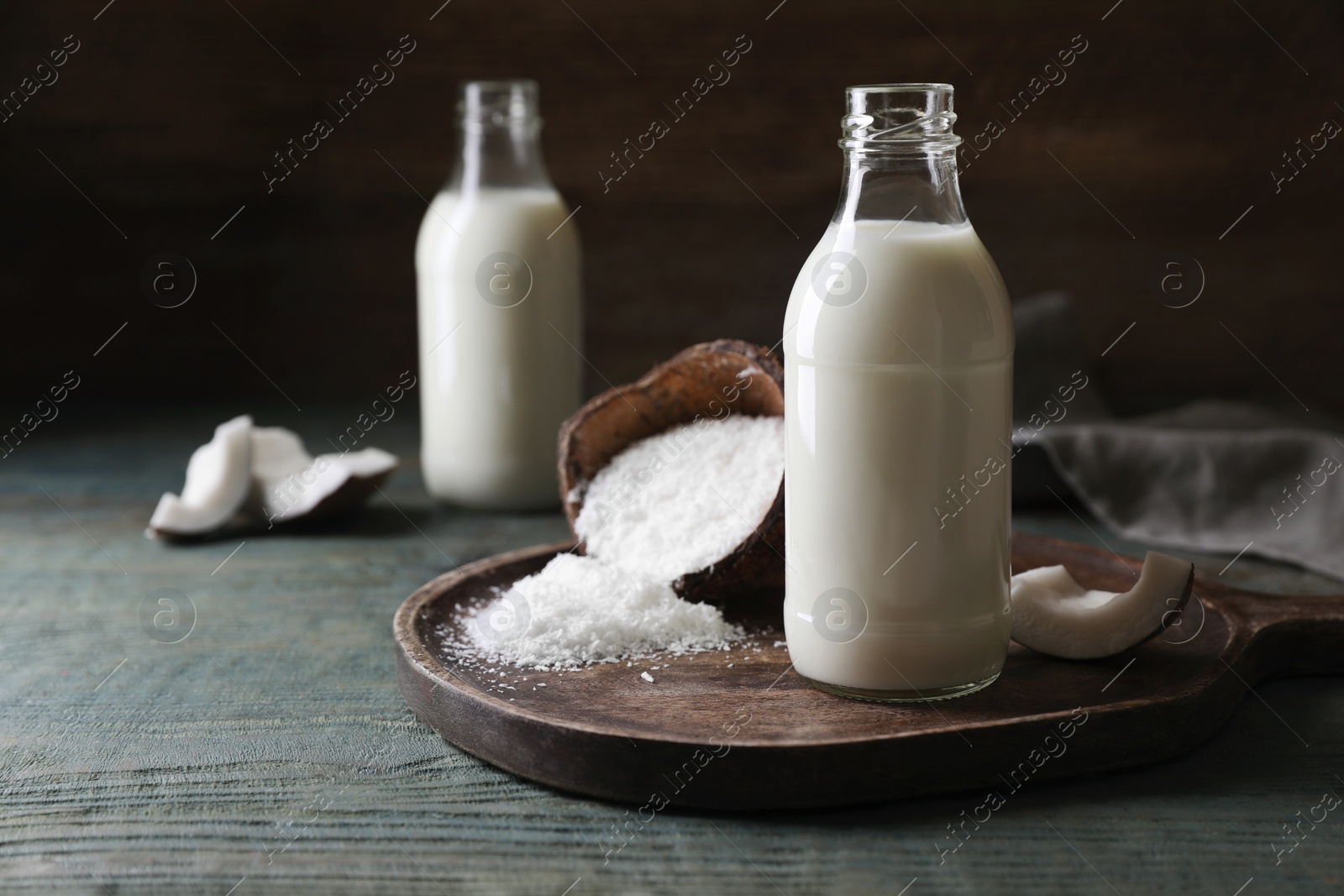 Photo of Delicious coconut milk, flakes and nut pieces on wooden table, space for text