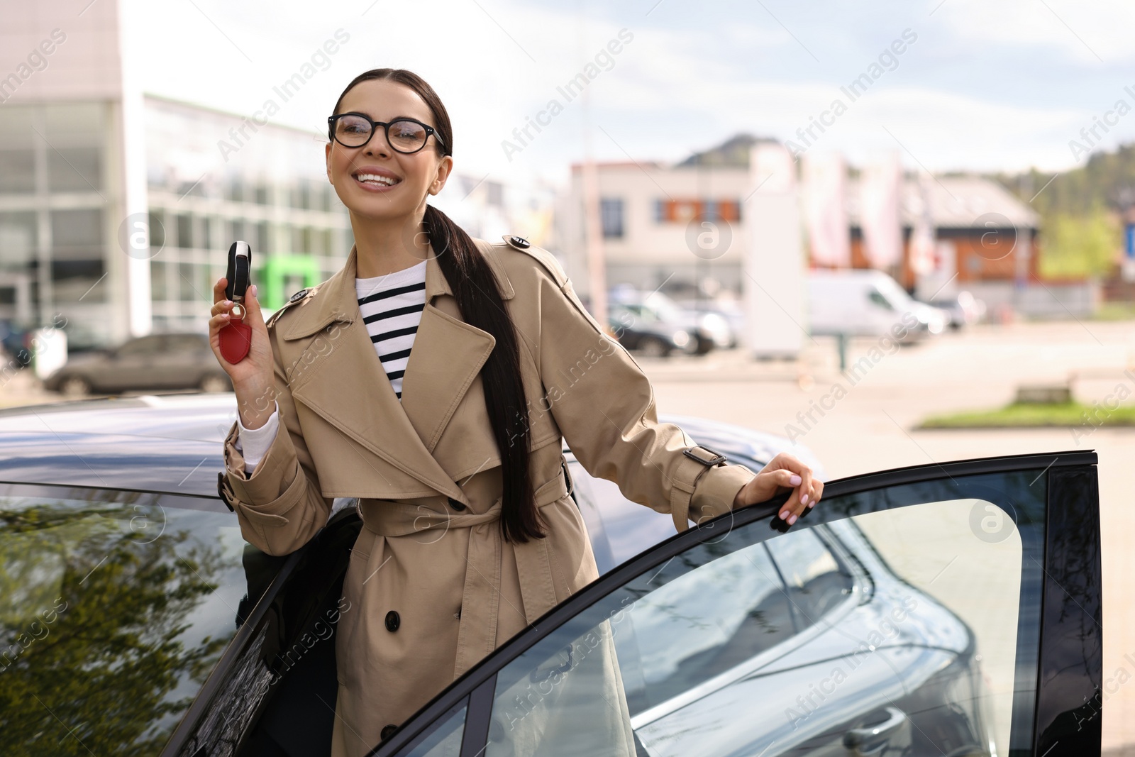 Photo of Woman holding car flip key near her vehicle outdoors