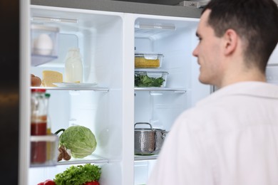 Photo of Man near refrigerator in kitchen at home, selective focus