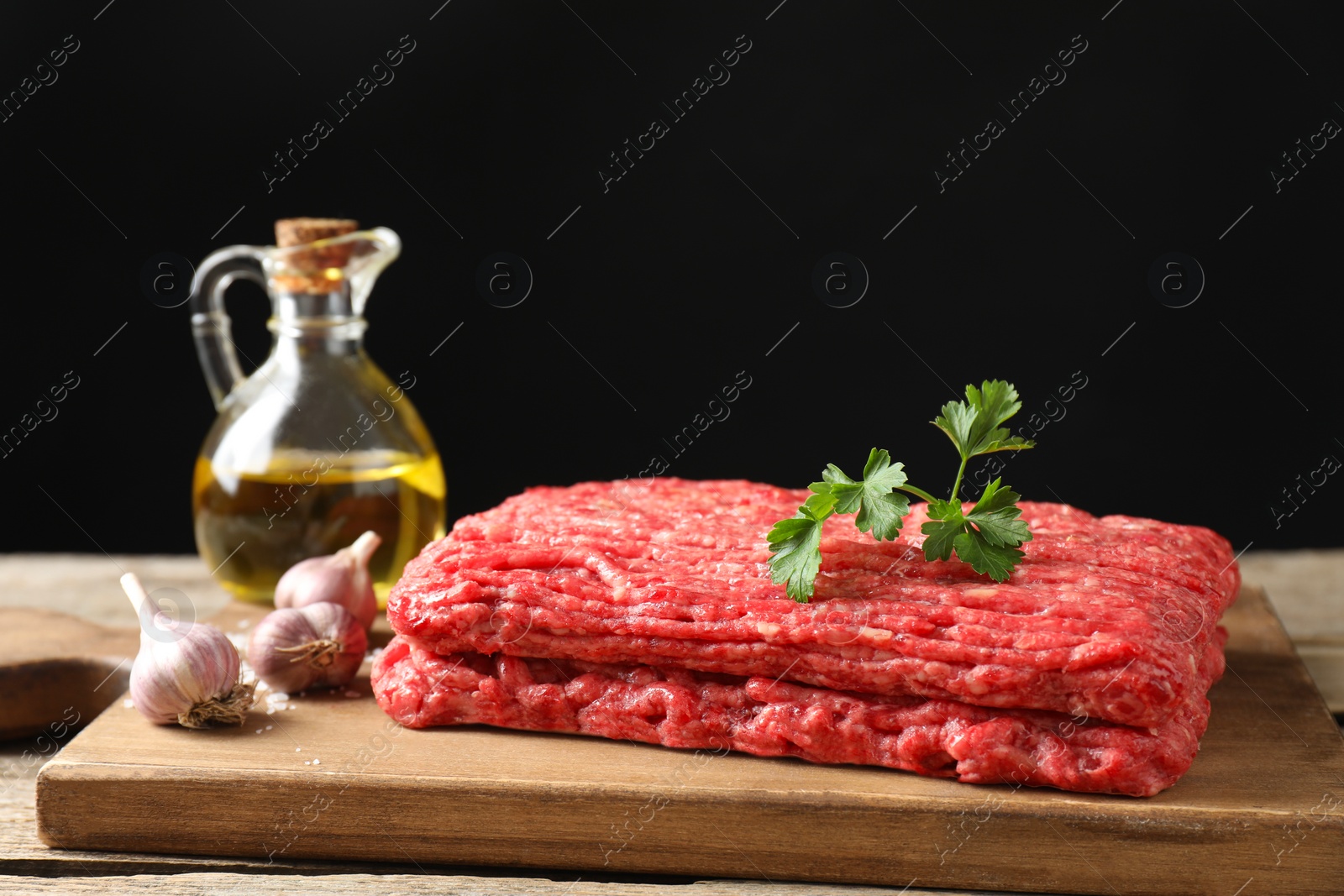 Photo of Raw ground meat, garlic, oil and parsley on table