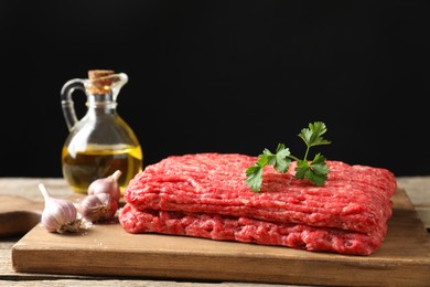 Photo of Raw ground meat, garlic, oil and parsley on table