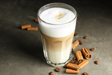 Delicious latte macchiato and cinnamon on grey table