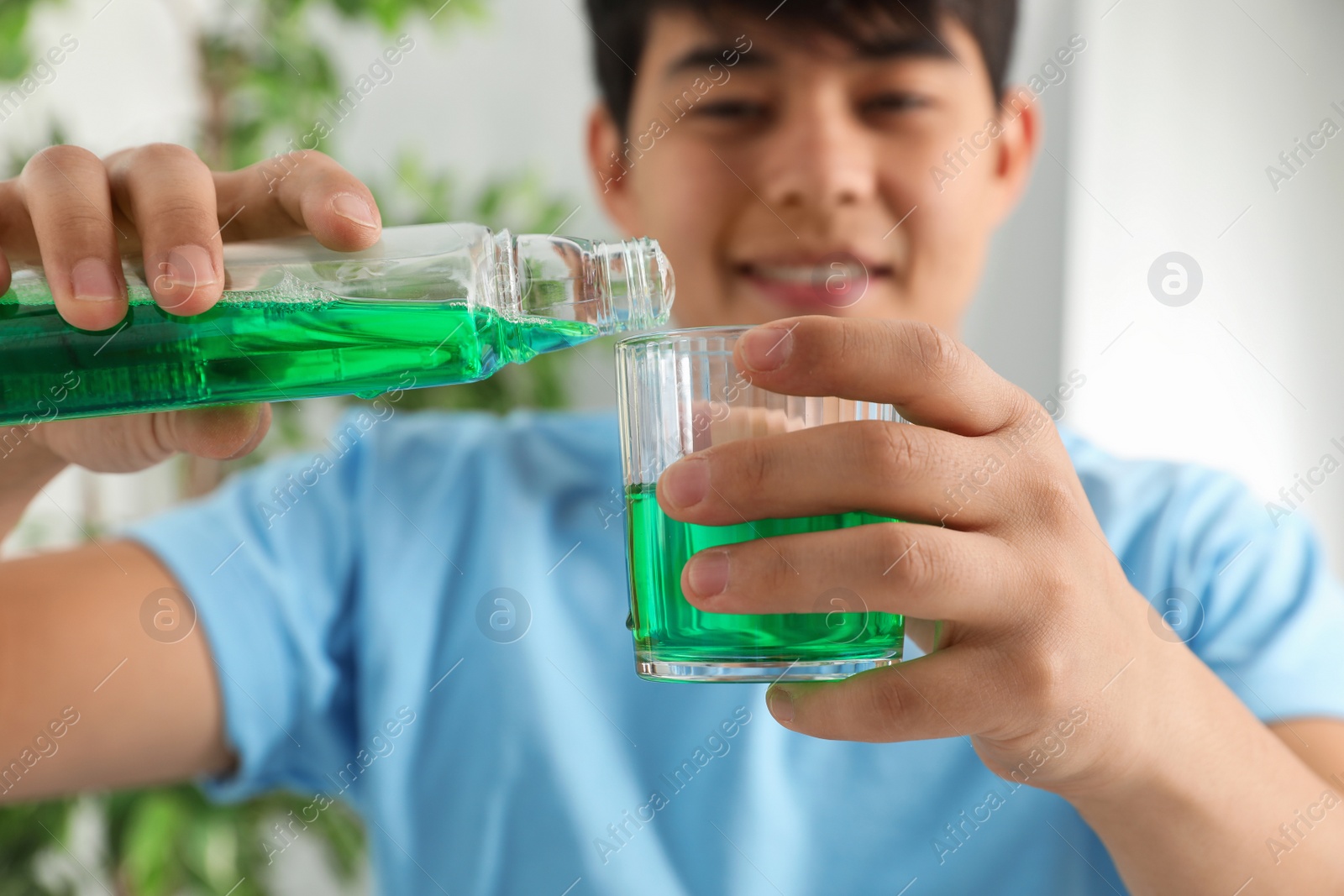 Photo of Man pouring mouthwash from bottle into glass, closeup. Teeth care