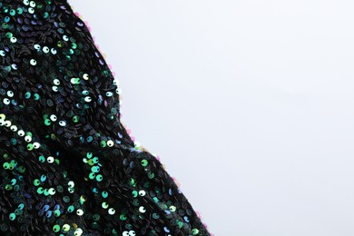 Photo of Dark shiny sequin fabric on white background, top view. Space for text