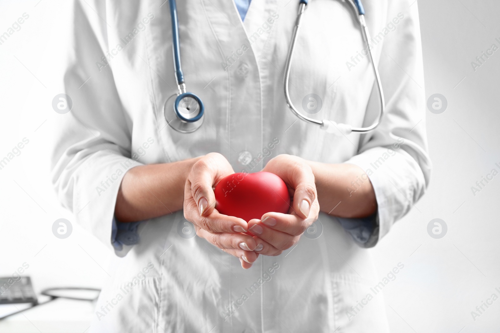 Photo of Doctor holding red heart indoors, closeup view