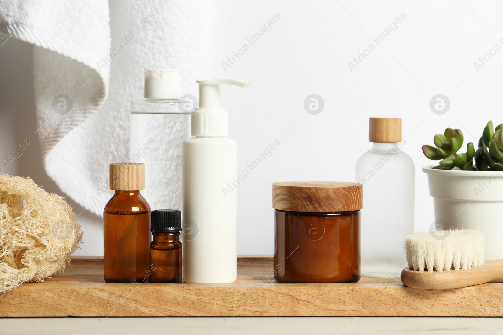 Photo of Different bath accessories and personal care products on light table near white wall