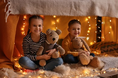 Photo of Kids with toys playing in decorated play tent at home