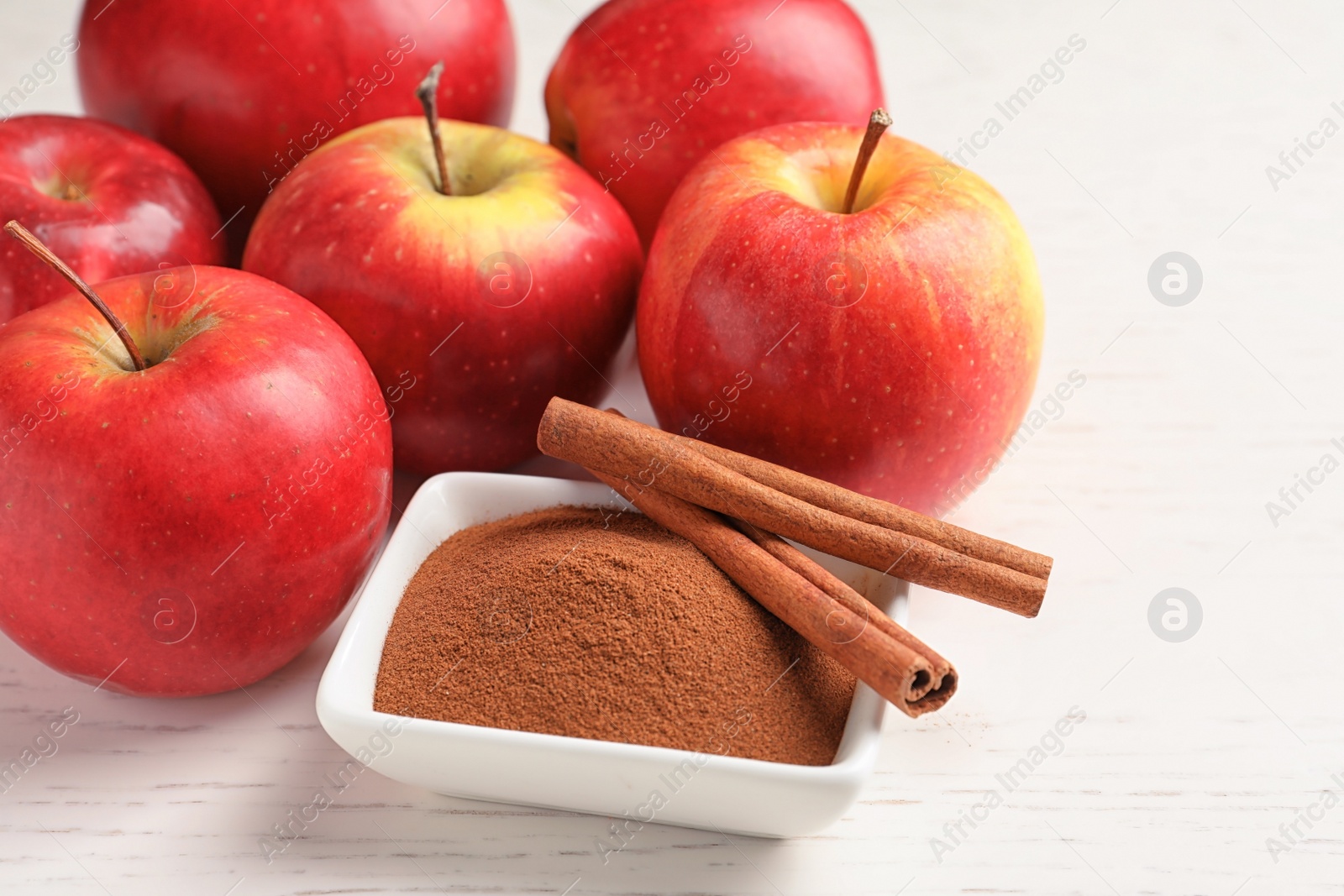 Photo of Fresh apples with cinnamon sticks and powder on wooden table