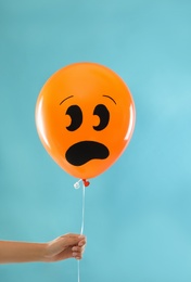 Photo of Woman holding spooky balloon for Halloween party on blue background