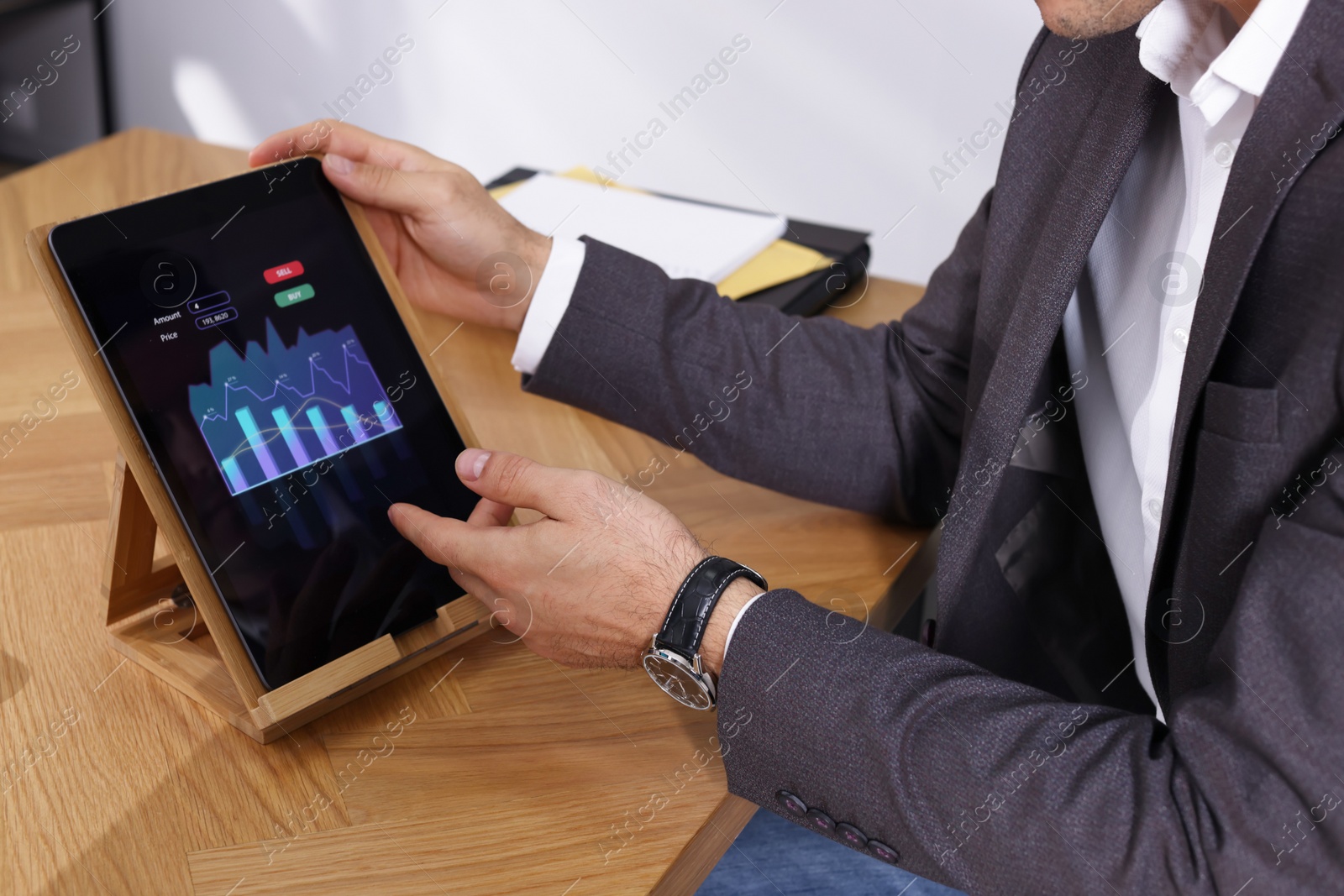 Photo of Businessman working with tablet at table, closeup. Forex trading