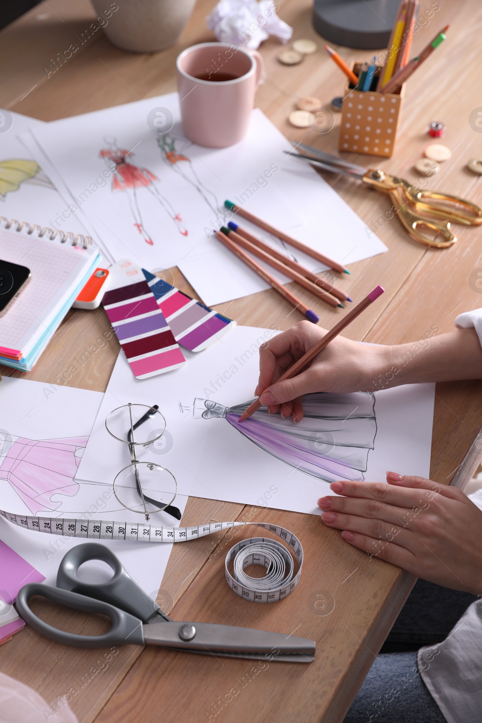 Photo of Fashion designer drawing sketch at wooden table, closeup