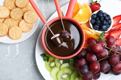 Flat lay composition with chocolate fondue on grey background