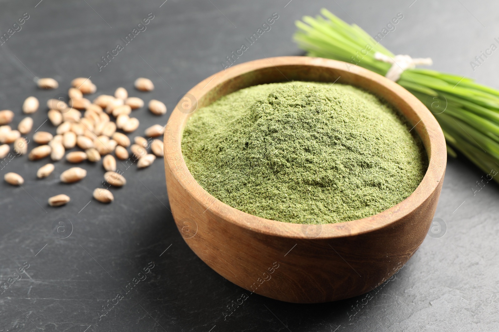 Photo of Wheat grass powder in bowl on grey table, closeup