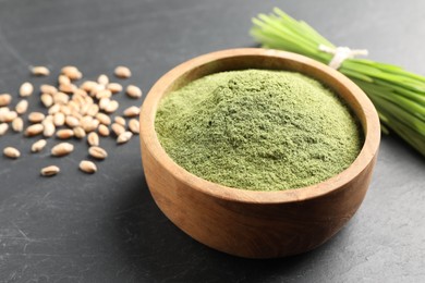 Photo of Wheat grass powder in bowl on grey table, closeup