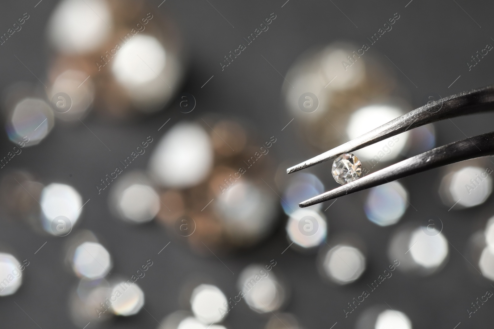 Photo of Tweezers with beautiful gemstone on blurred background. Space for text