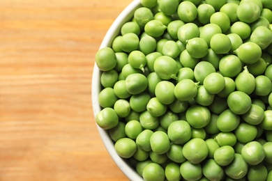 Photo of Bowl with green peas on wooden background, closeup