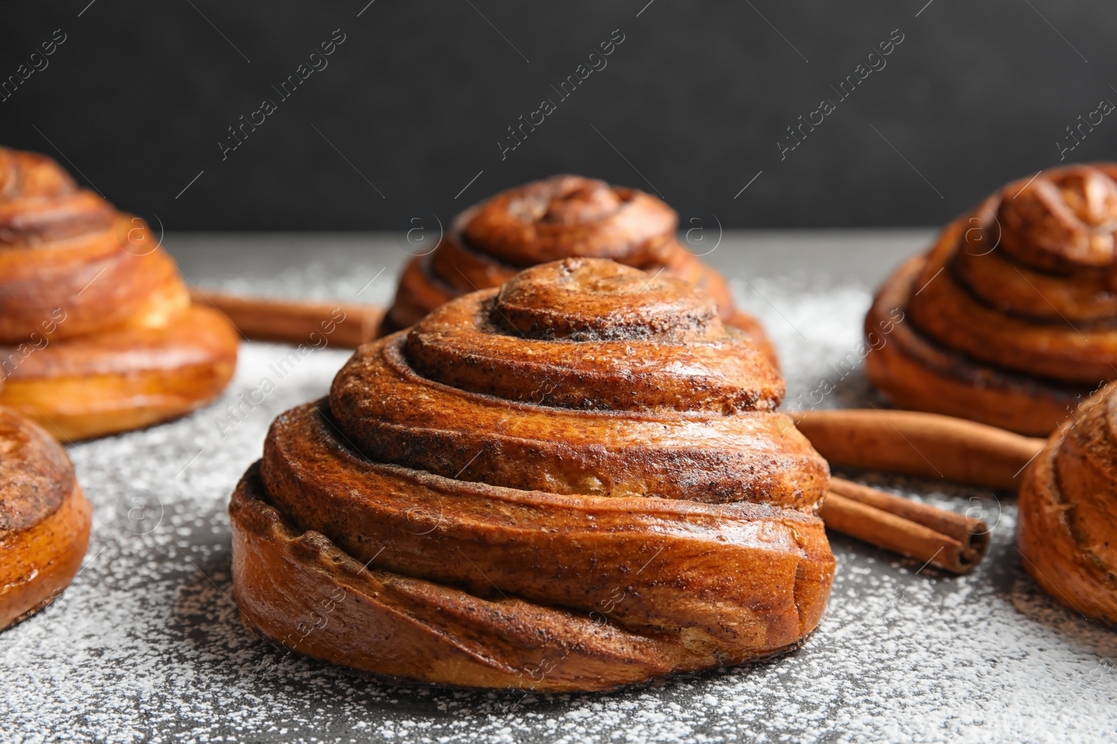 Photo of Cinnamon rolls and sugar powder on table, closeup