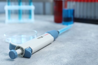 Photo of Laboratory analysis. Micropipette with liquid and petri dish on light grey table, closeup. Space for text