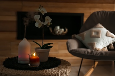 Photo of Aroma oil diffuser, burning candle and beautiful potted orchid flower on table in living room. Space for text
