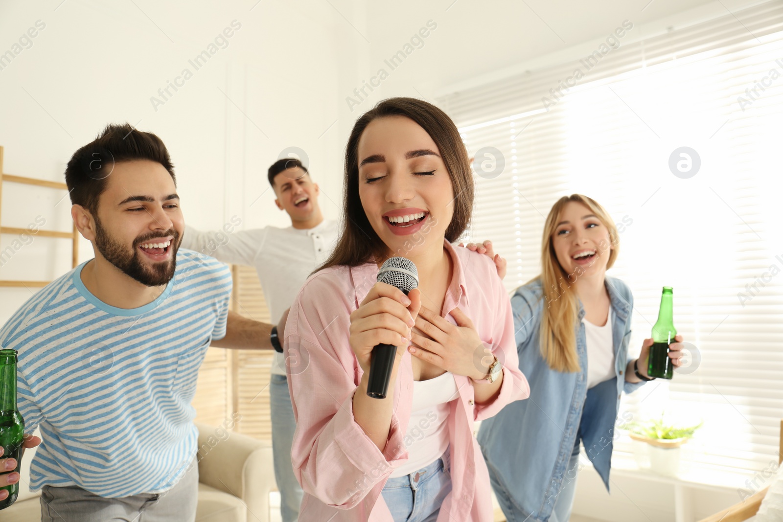 Photo of Young woman singing karaoke with friends at home