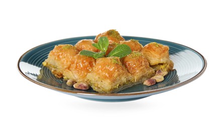 Plate of delicious baklava with pistachio nuts and mint on white background