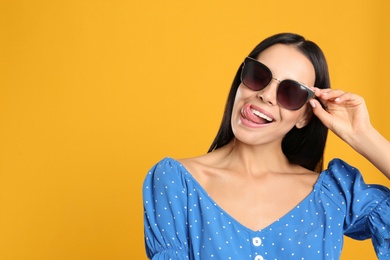 Photo of Beautiful woman wearing sunglasses on yellow background. Space for text