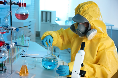 Scientist in chemical protective suit working at laboratory. Virus research