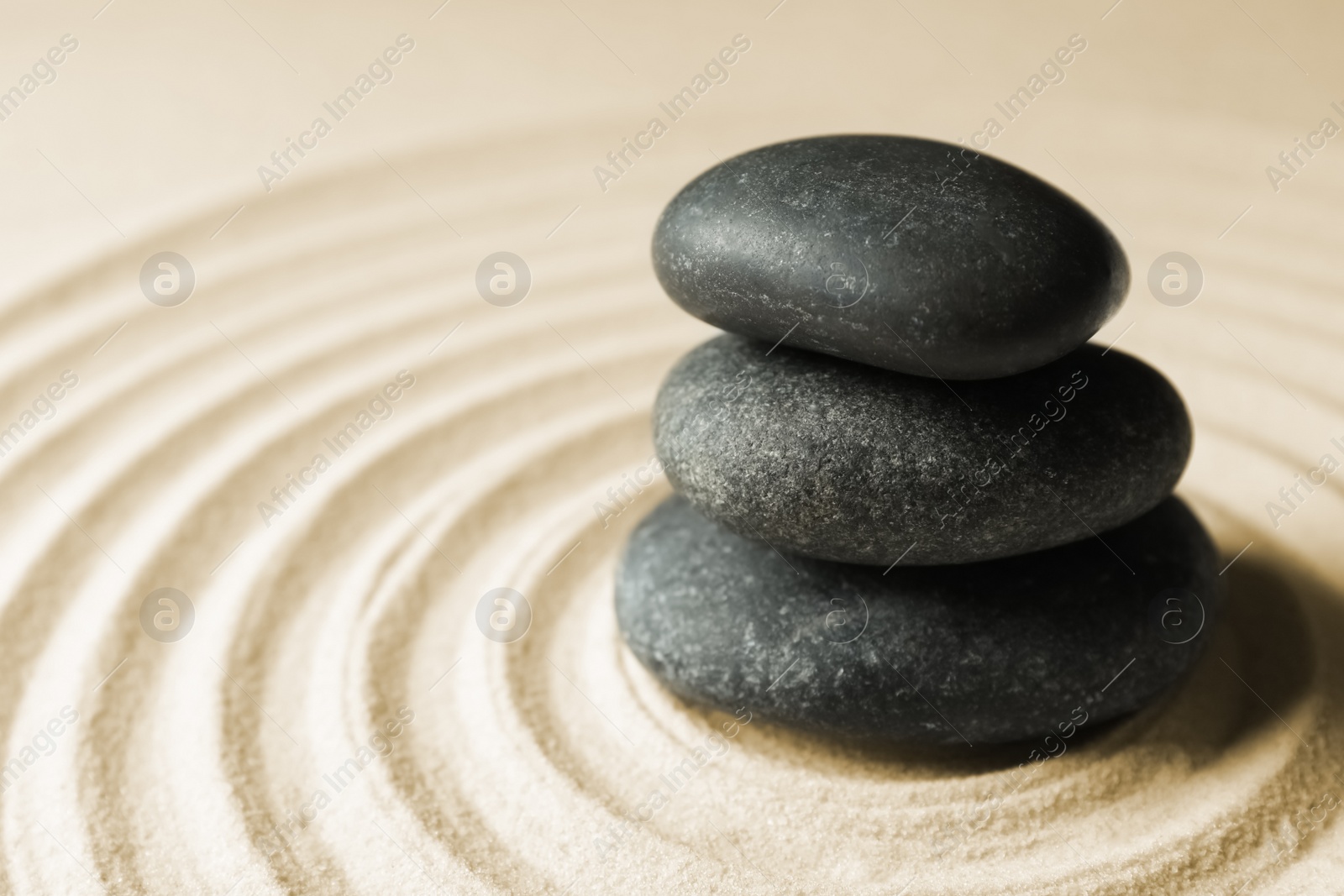 Photo of Stacked zen garden stones on sand with pattern, space for text. Meditation and harmony