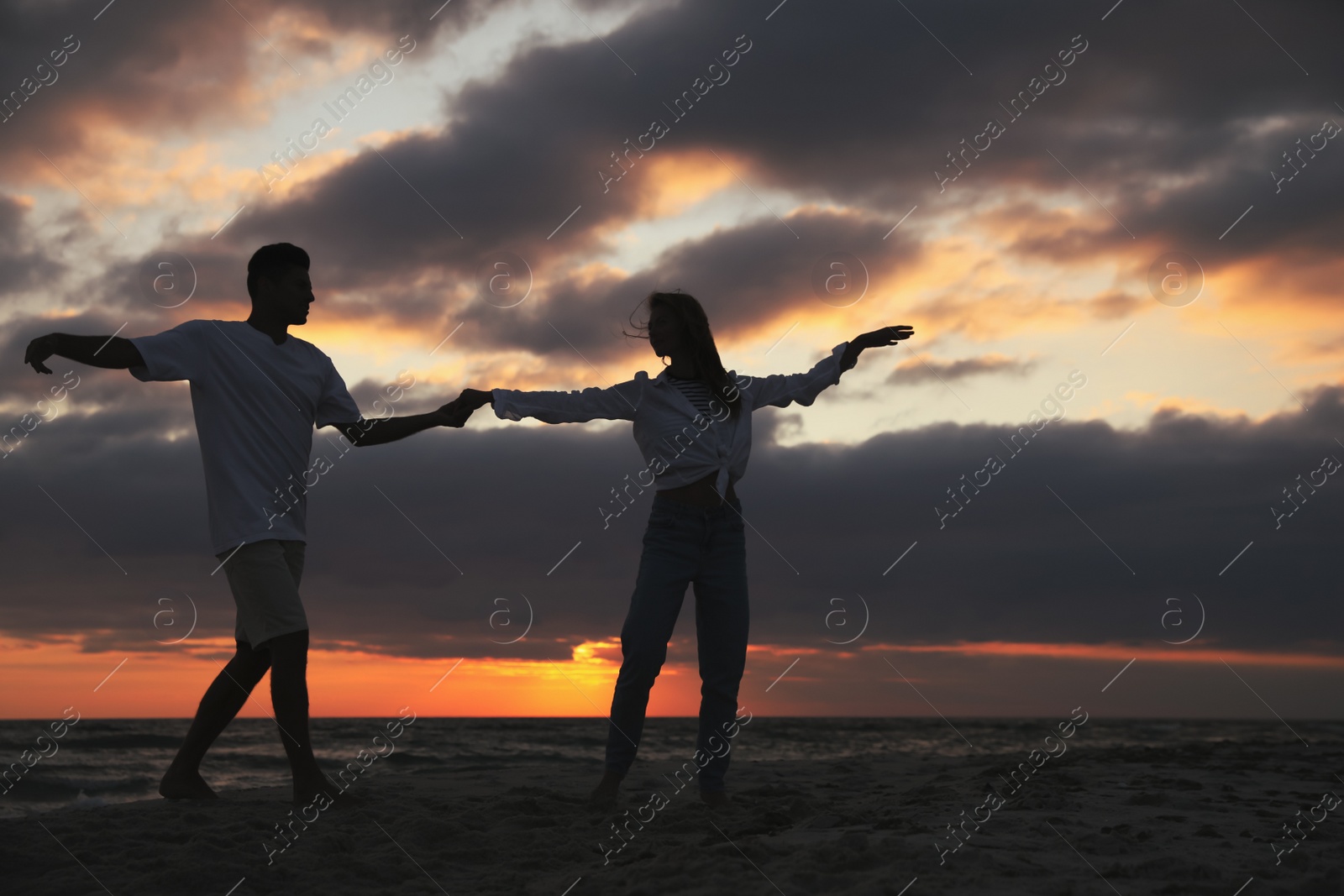 Photo of Happy couple dancing on beach at sunset