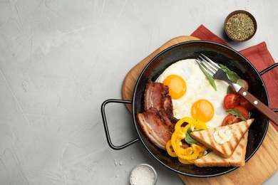 Tasty breakfast with fried eggs on grey table, flat lay. Space for text