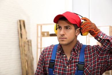 Worker wearing safety headphones indoors, space for text. Hearing protection device