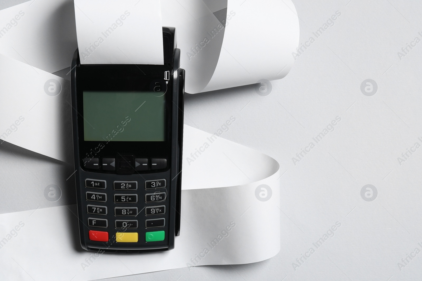 Photo of Payment terminal with thermal paper for receipt on light grey background, top view. Space for text