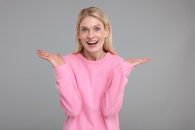 Portrait of happy surprised woman on grey background