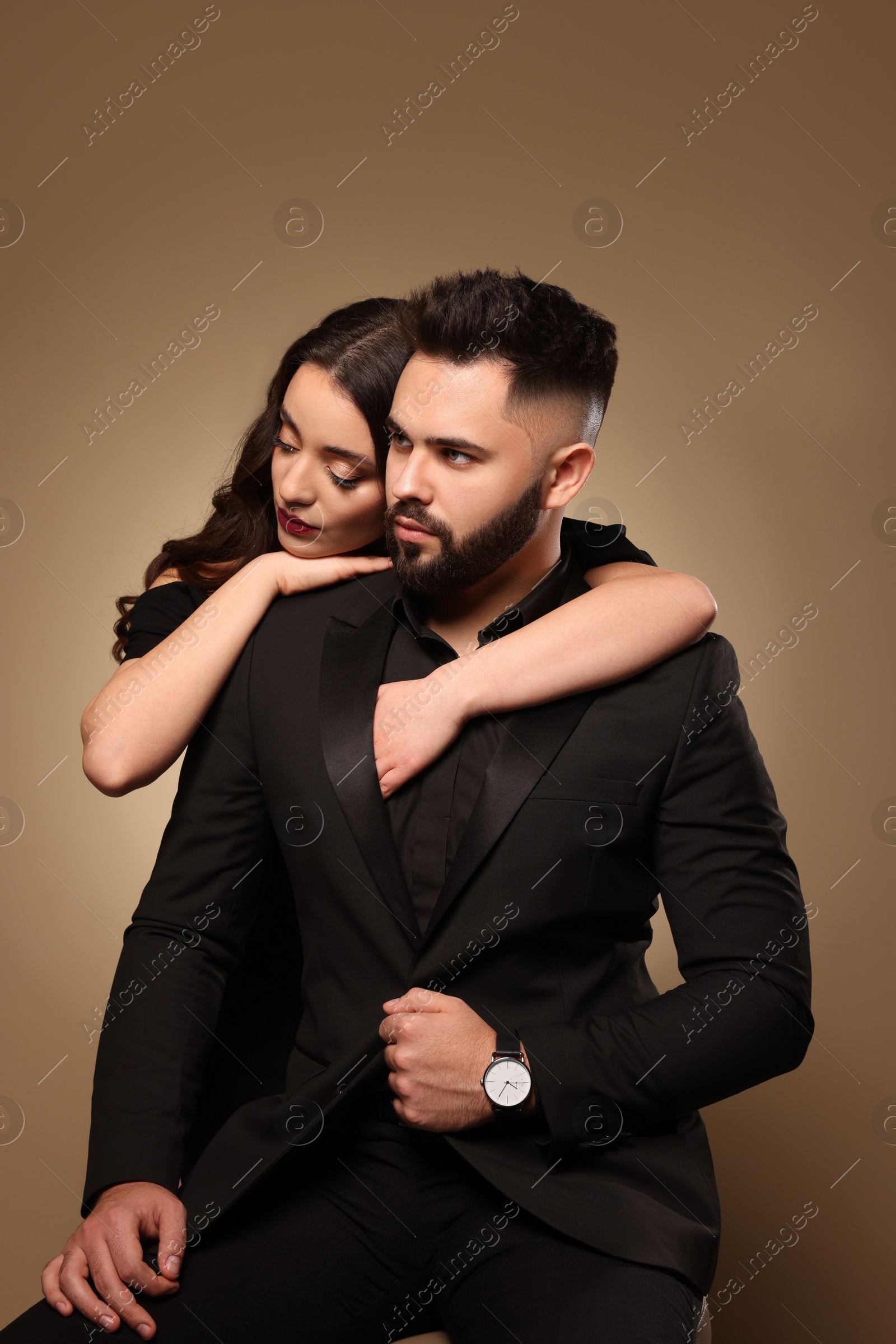 Photo of Handsome bearded man with sexy lady on light brown background