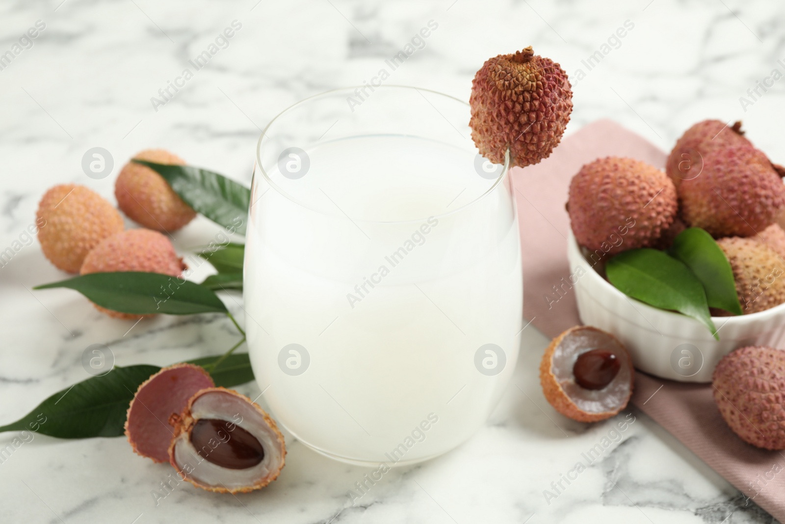 Photo of Lychee juice and fresh fruits on white marble table