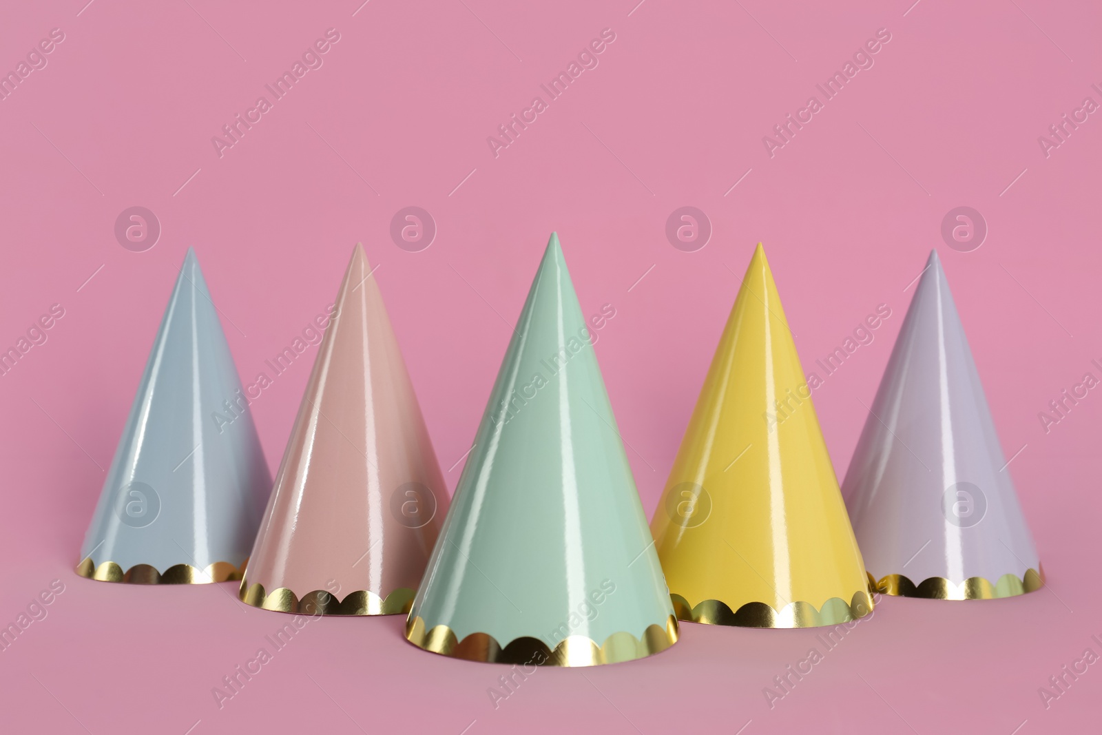 Photo of Different colorful party hats on pink background
