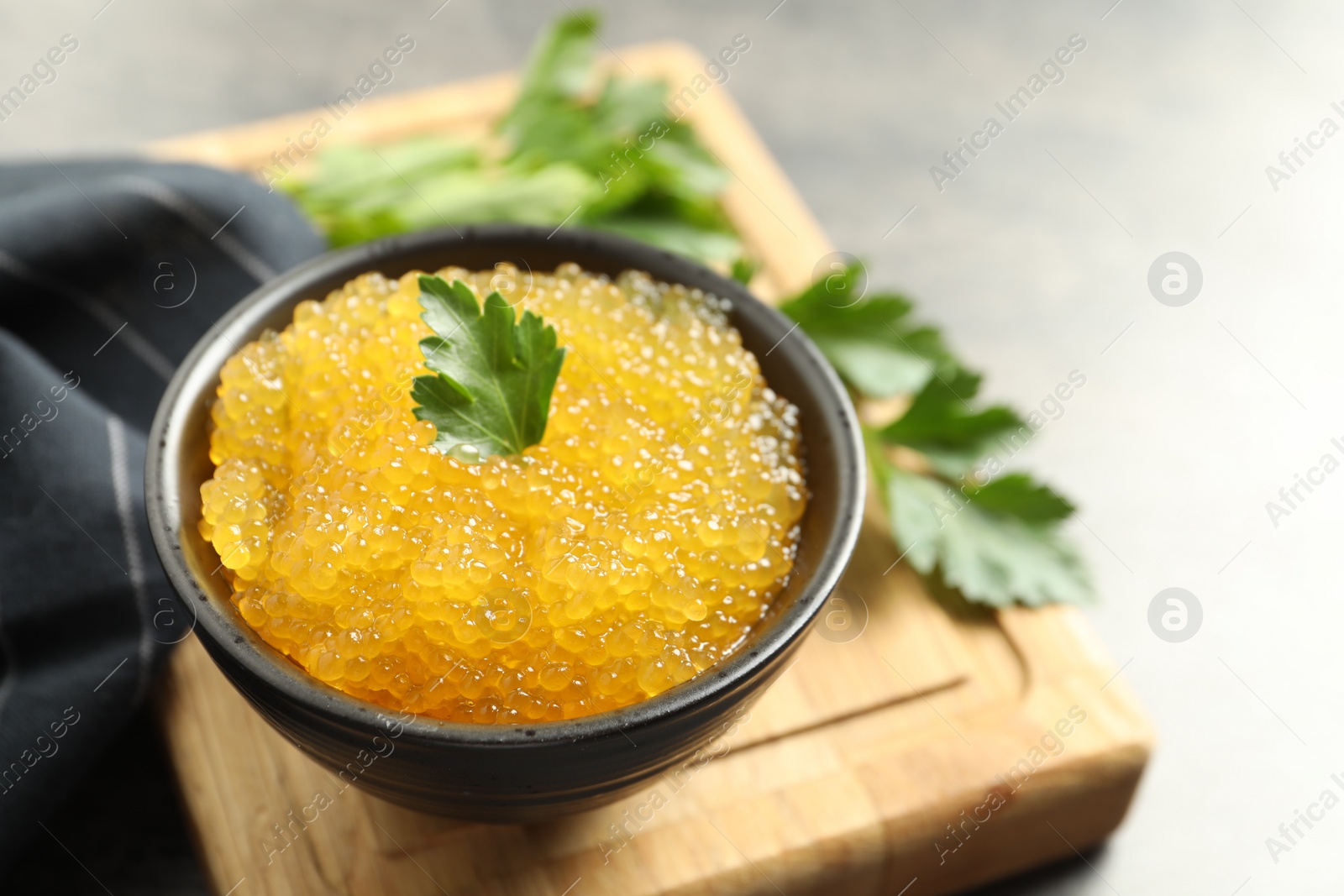 Photo of Fresh pike caviar in bowl and parsley on table, closeup