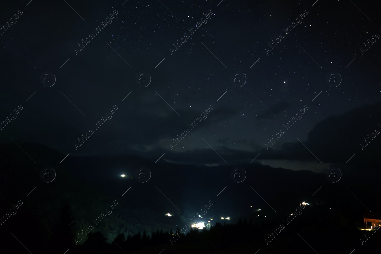 Photo of Picturesque view of small town in mountains and beautiful starry sky at night