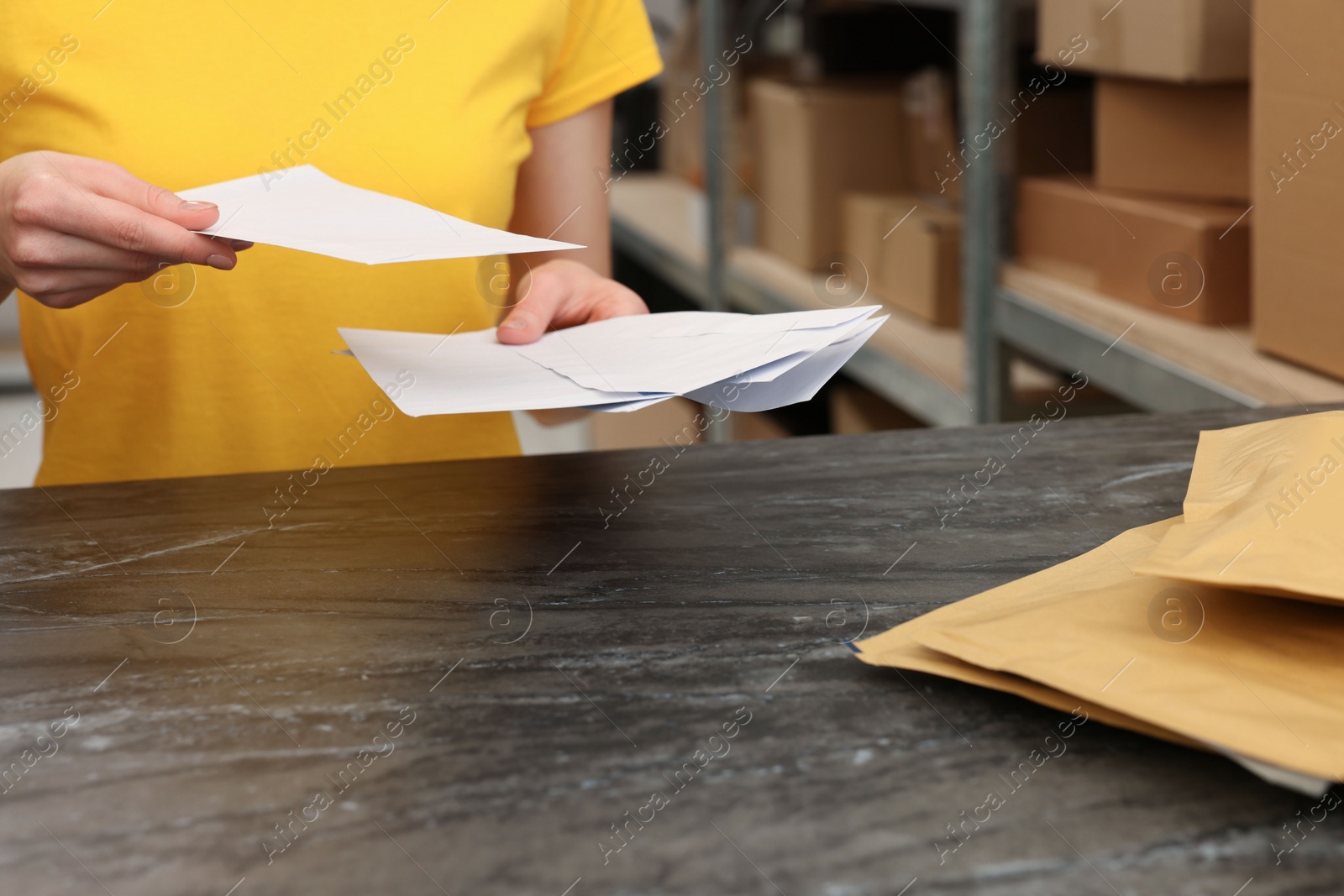 Photo of Post office worker with envelopes at counter indoors, closeup