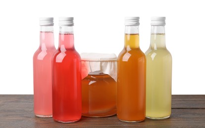 Delicious kombucha in glass bottles and jar on wooden table against white background