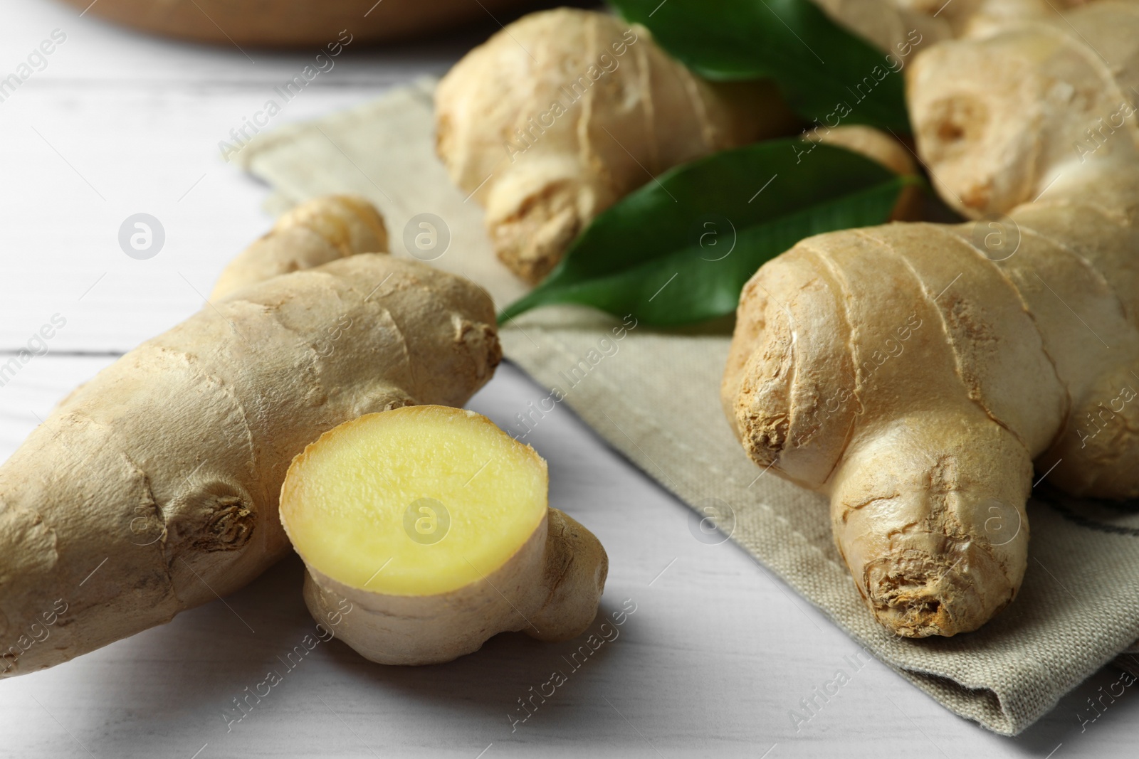 Photo of Fresh ginger with leaves on white wooden table