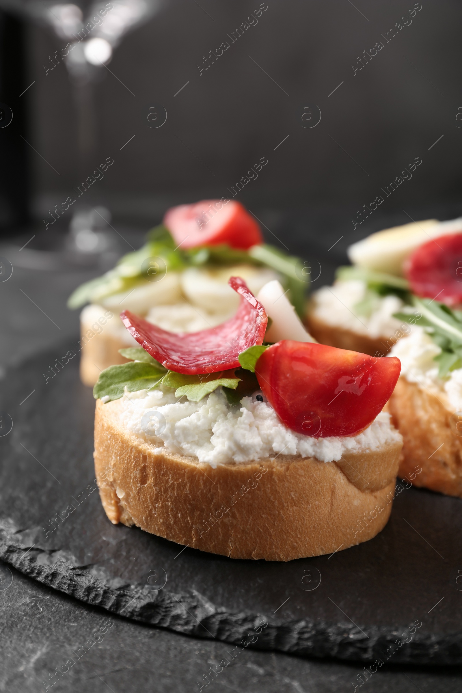 Photo of Delicious bruschettas with sausage and cheese on black table, closeup