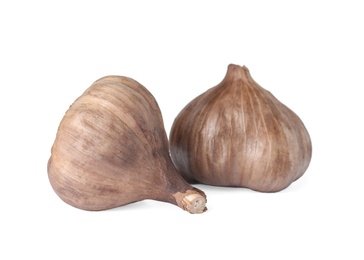 Unpeeled bulbs of black garlic on white background