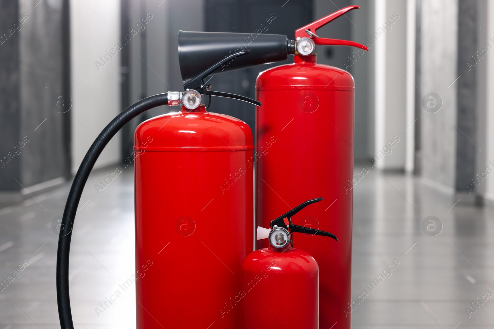 Photo of Three red fire extinguishers in hall, closeup