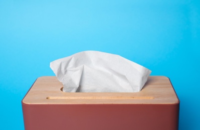 Holder with paper tissues on light blue background, closeup