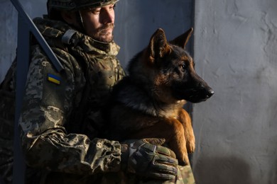 Ukrainian soldier with German shepherd dog near wall outdoors