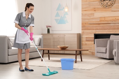 Photo of Chambermaid washing floor with mop in hotel room. Space for text