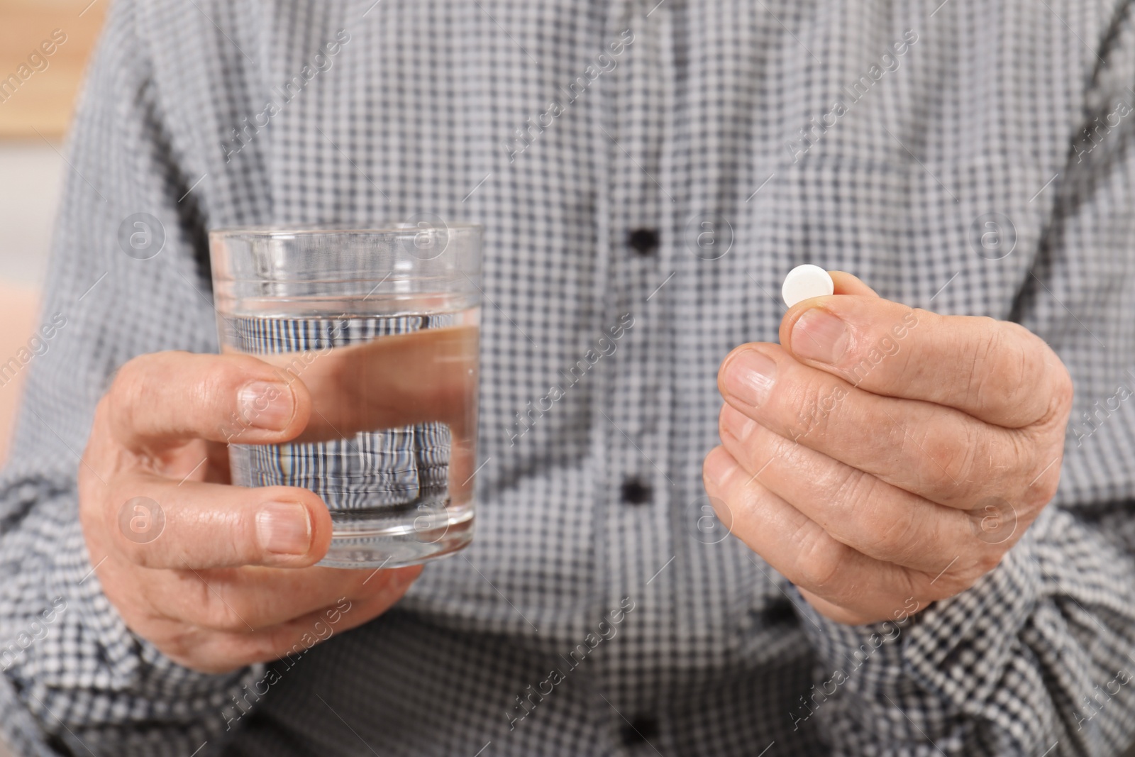 Photo of Senior man holding pill and glass of water, closeup