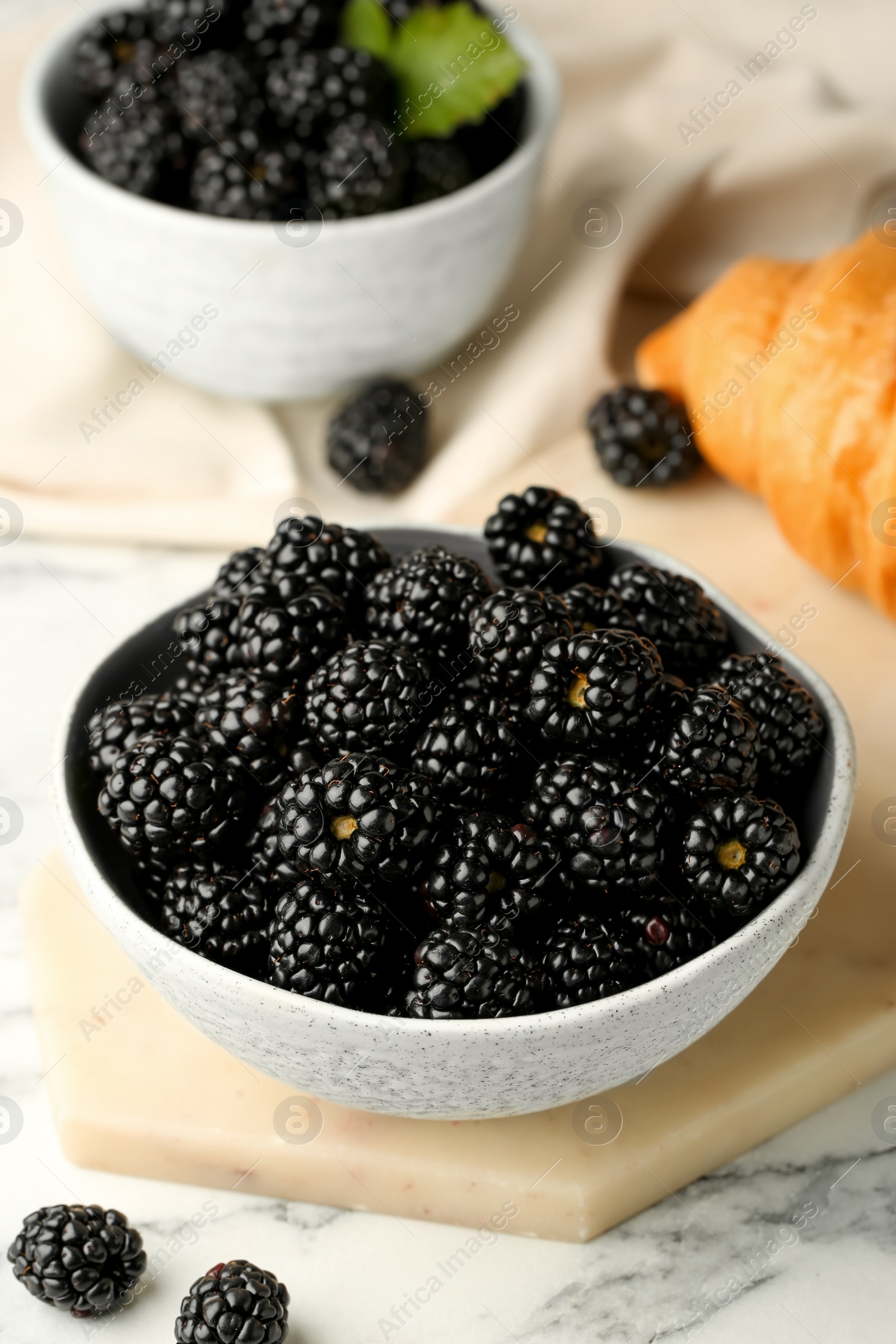 Photo of Bowl of fresh ripe blackberries on white marble table